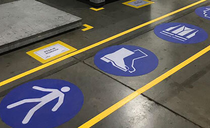 PPE floor signs inside marked aisle way indicating PPE area